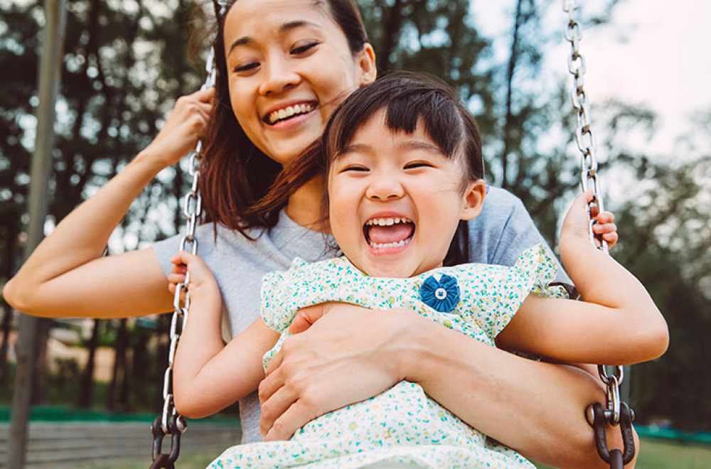 Mother and daughter laughing on a swing